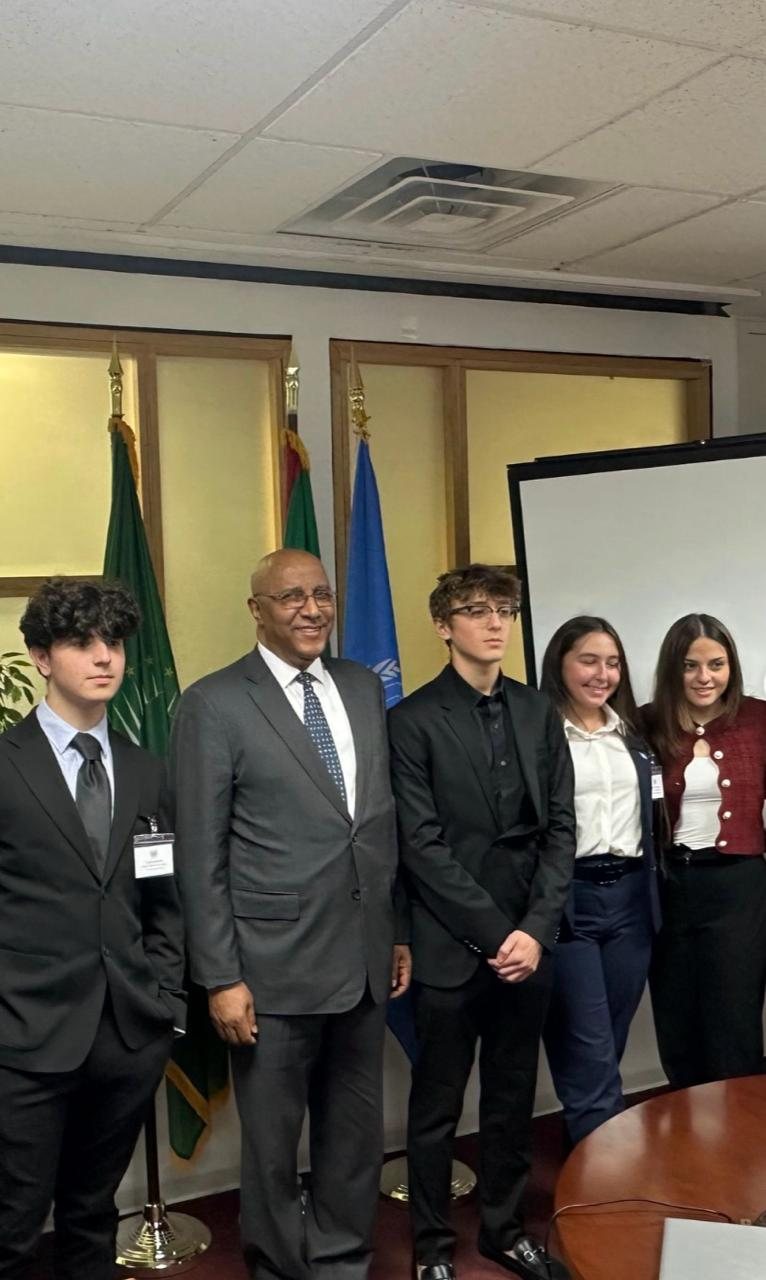 Max and fellow delegates with a diplomat beside national flags